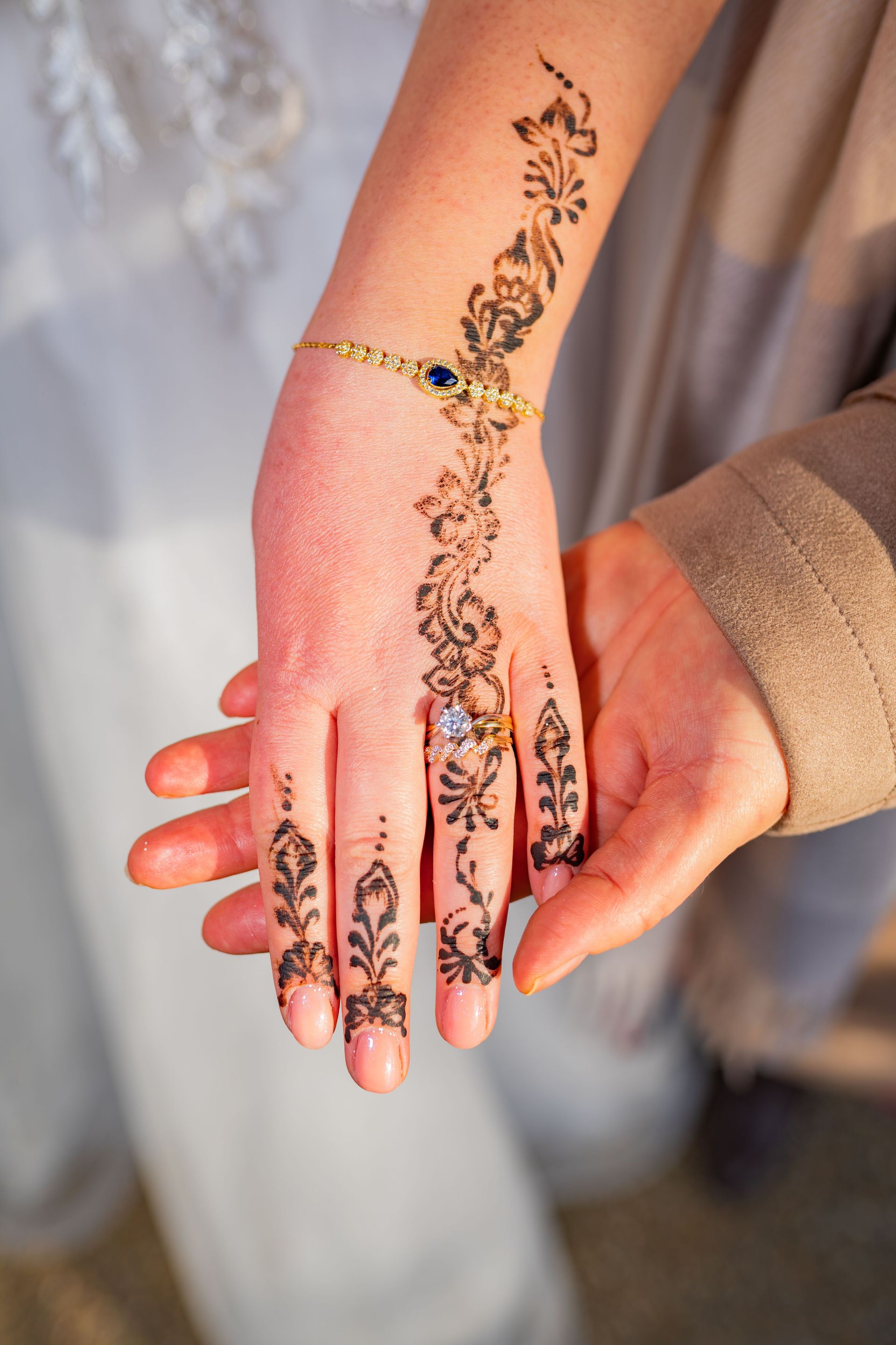 Close-up of a bride's hand adorned with intricate henna and jewelry, depicting cultural elegance.